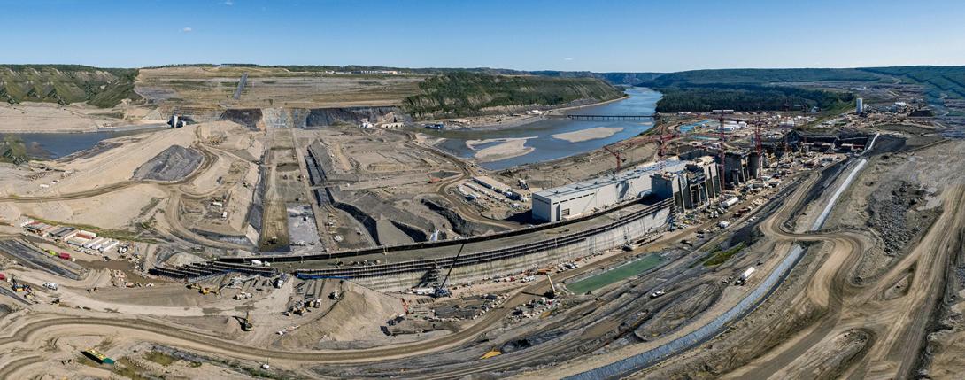 Aerial view of the earthfill dam, approach channel and roller compacted concrete ramp, dam and core buttress, and powerhouse and spillways. | August 2021