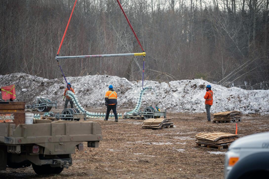 The line crew assist the helicopter to pick up the v-string insulator assembly for installation. |January 2022