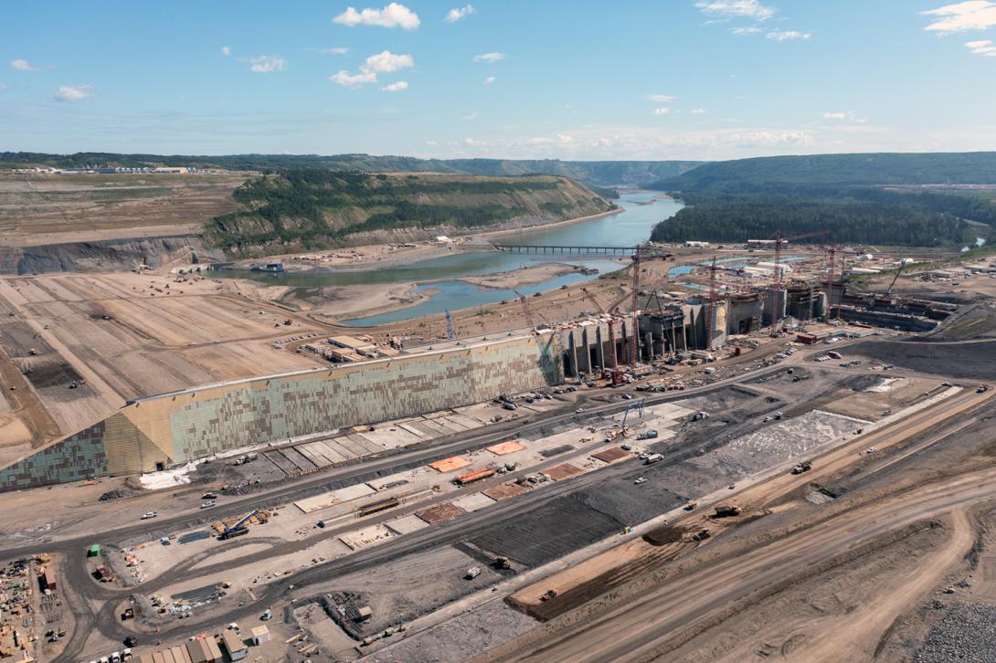 Construction at the approach channel in the foreground with the roller compacted concrete buttress in front of the dam at left. | July 2022